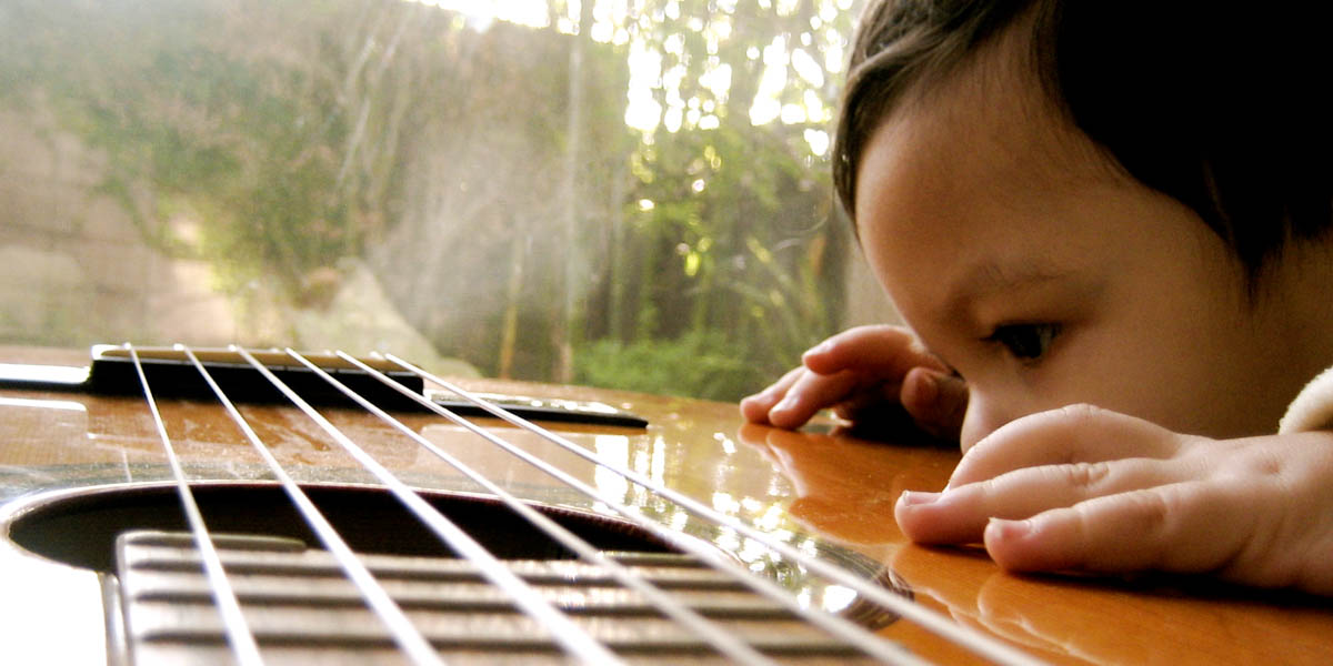 CHILD LOOKING AT GUITAR