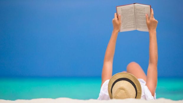 Young woman is reading on tropical white beach
