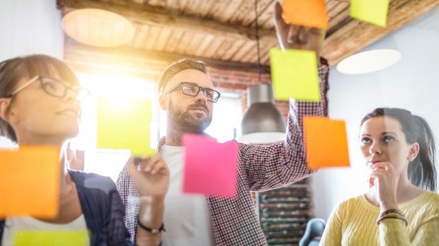 PEOPLE LOOKING AT POST-IT NOTES