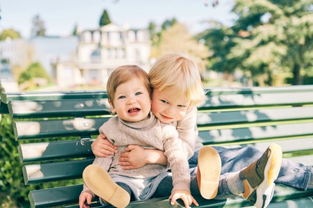 two adorable siblings resting on the bench in sunny park