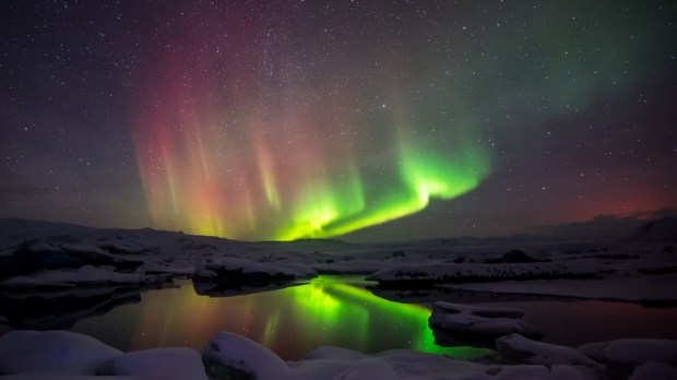A beautiful green and red aurora dancing over the Jokulsarlon lagoon, Iceland
