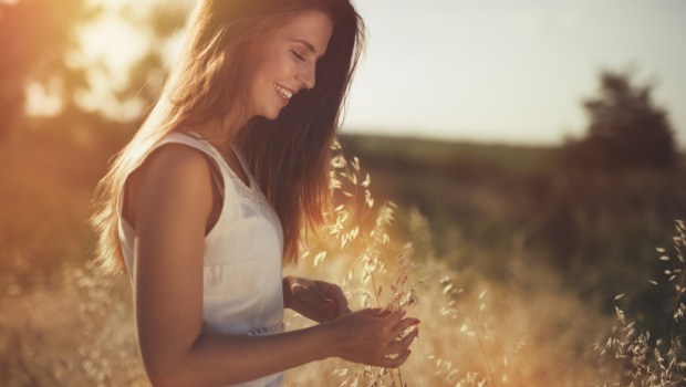 Beautiful carefree woman in fields being happy outdoors