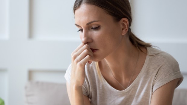 Close up of sad pensive millennial woman sit alone