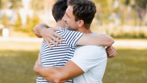 father and teenager son hugging outside