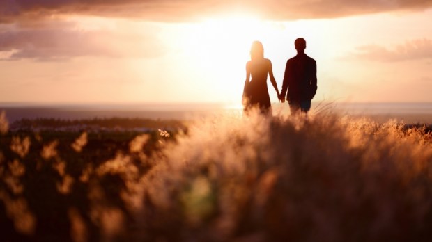 Young couple enjoying the sunset in the meadow