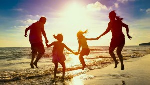 Family jumping together at the beach at sunset