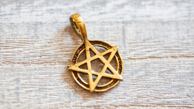 Brass golden color pentagram necklace on wooden background