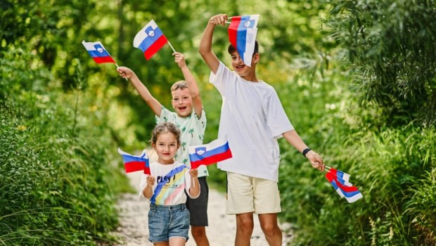Three kids hold slovenian flags in Triglav National Park, Slovenia