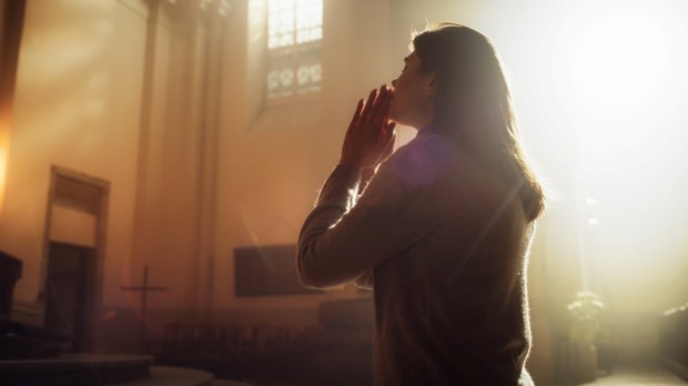 Christian Woman Getting on her Knees in Front of Altar and Starting to Pray in Church