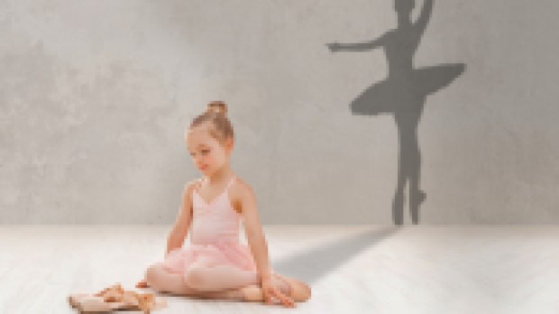 Little girl looking at pointe shoes, dreaming to become famous ballerina