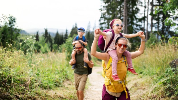 Family with small children hiking outdoors in summer nature.