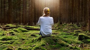Woman sitting in forest enjoys the silence and beauty of nature
