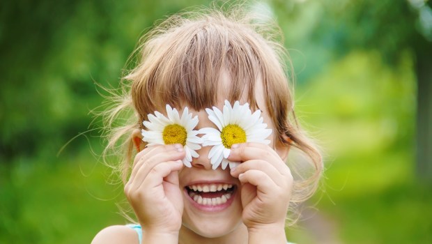 the girl is holding chamomile flowers in her hands