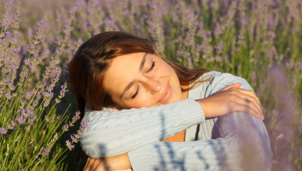 Happy woman relaxing with closed eyes sitting in lavender field