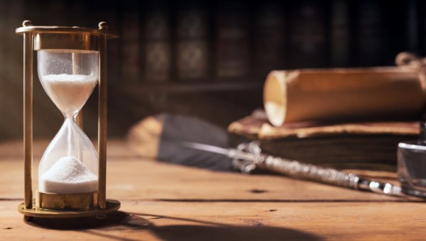 sand running through the hourglass on old wooden table