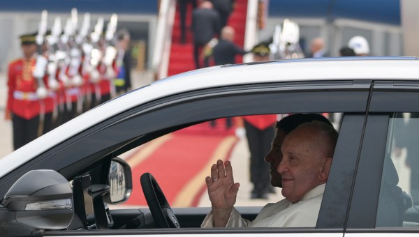 Pope Francis waves from a departing vehicle following his arrival at Soekarno-Hatta International Airport in Jakarta on September 3, 2024